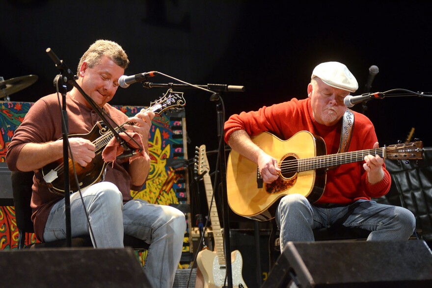 Two men on stage one plays mandolin and the other guitar